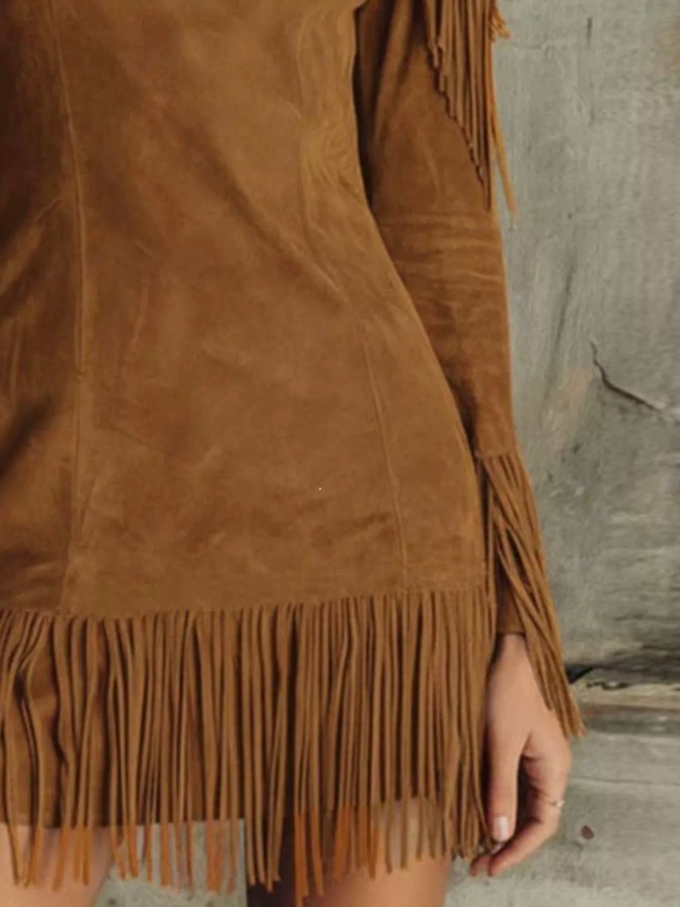 Close detail of the brown fringed cold shoulder mini dress hem and sleeve fringe