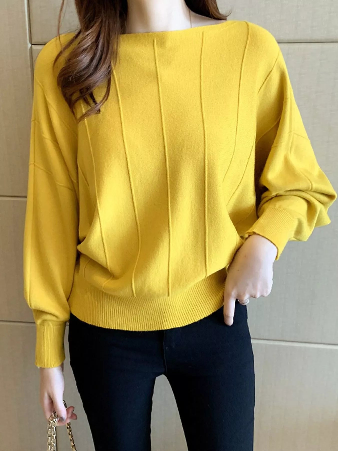 Front view of a yellow batwing sleeve knit top with vertical seams and ribbed hem.