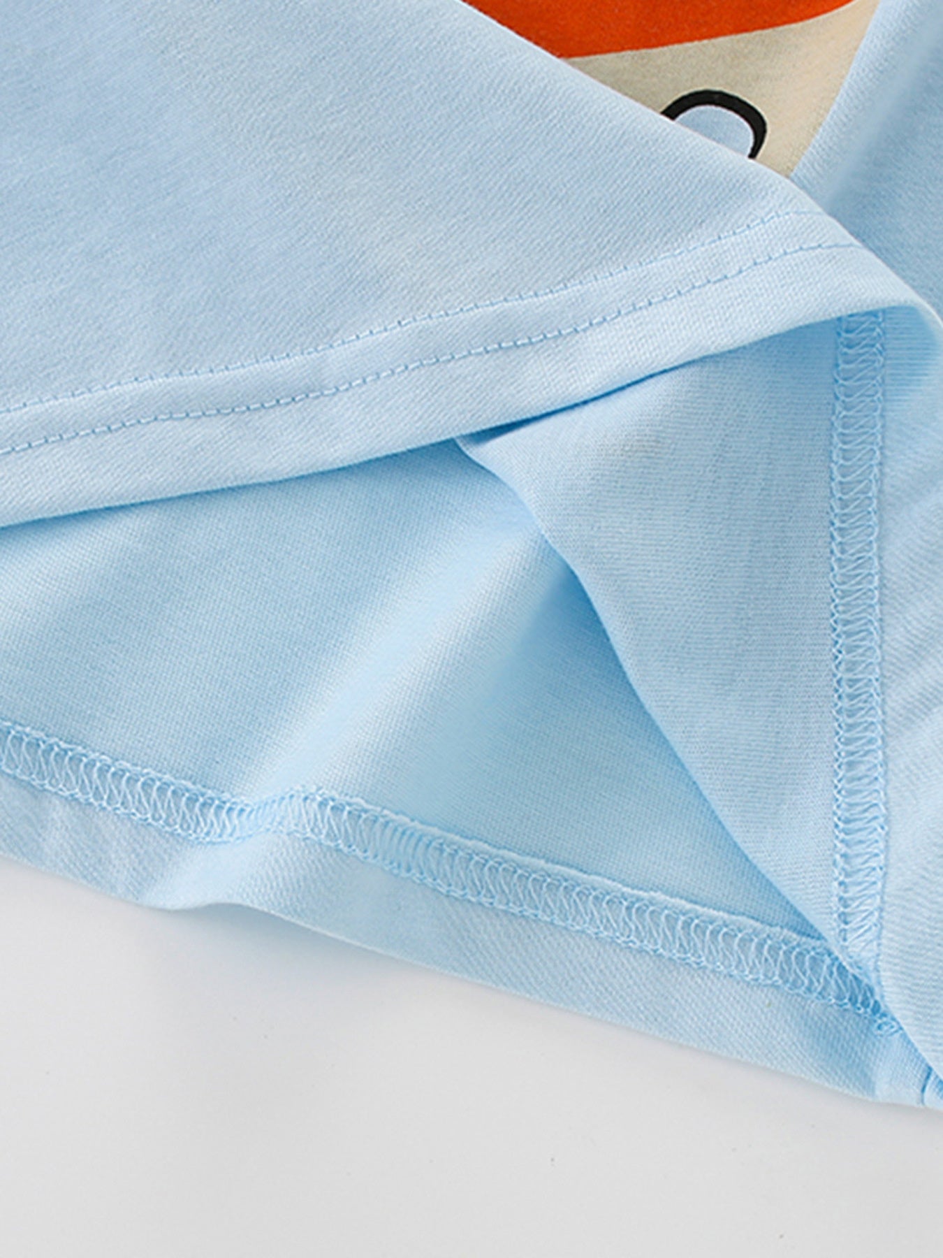Close view of the hem and side seam stitching on the light blue children's tee