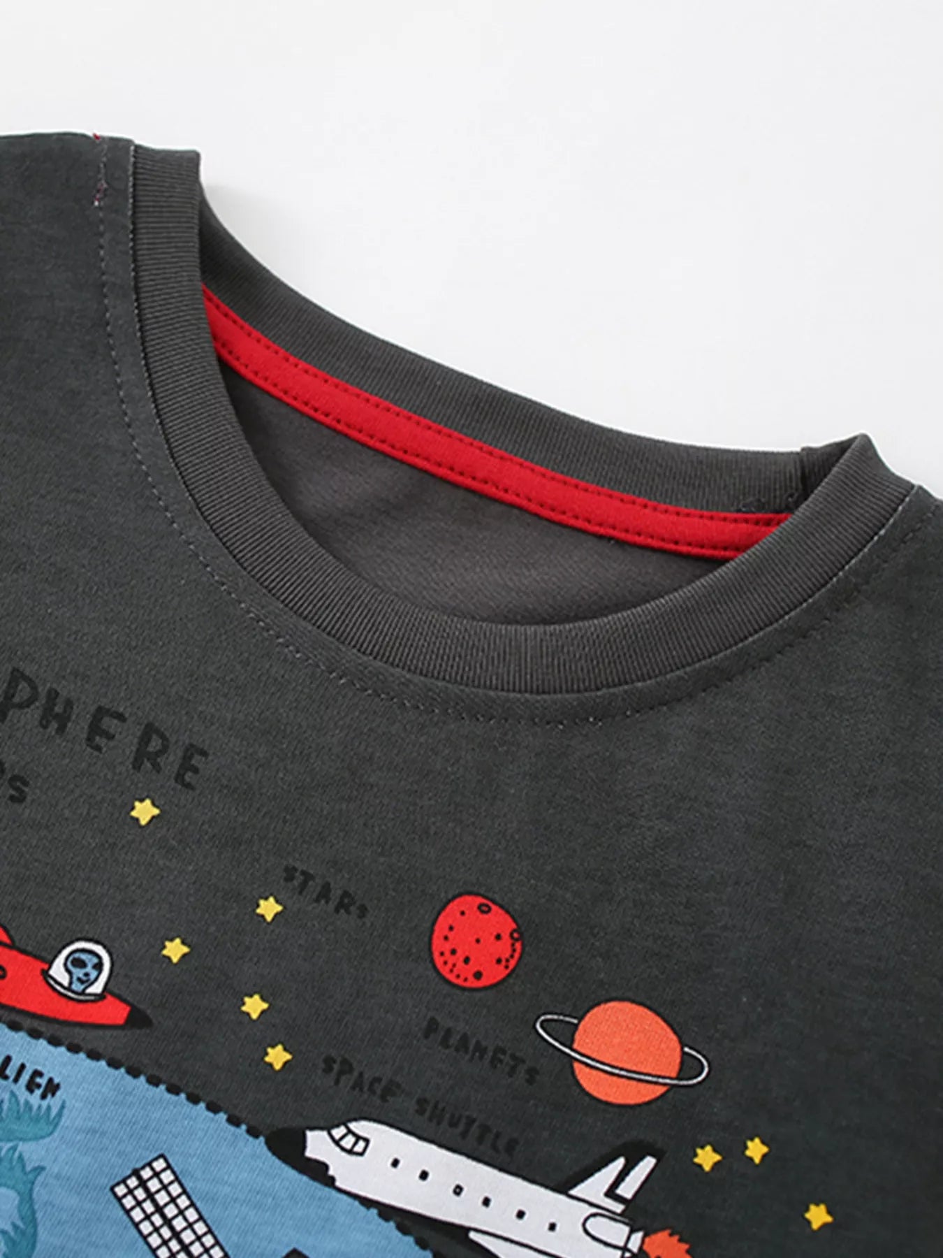 Close-up of the gray round neckline with red inner trim and cartoon planets above a space shuttle