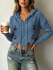 Dark blue knit zip up hooded sweater with red cherry appliques worn on model holding coffee
