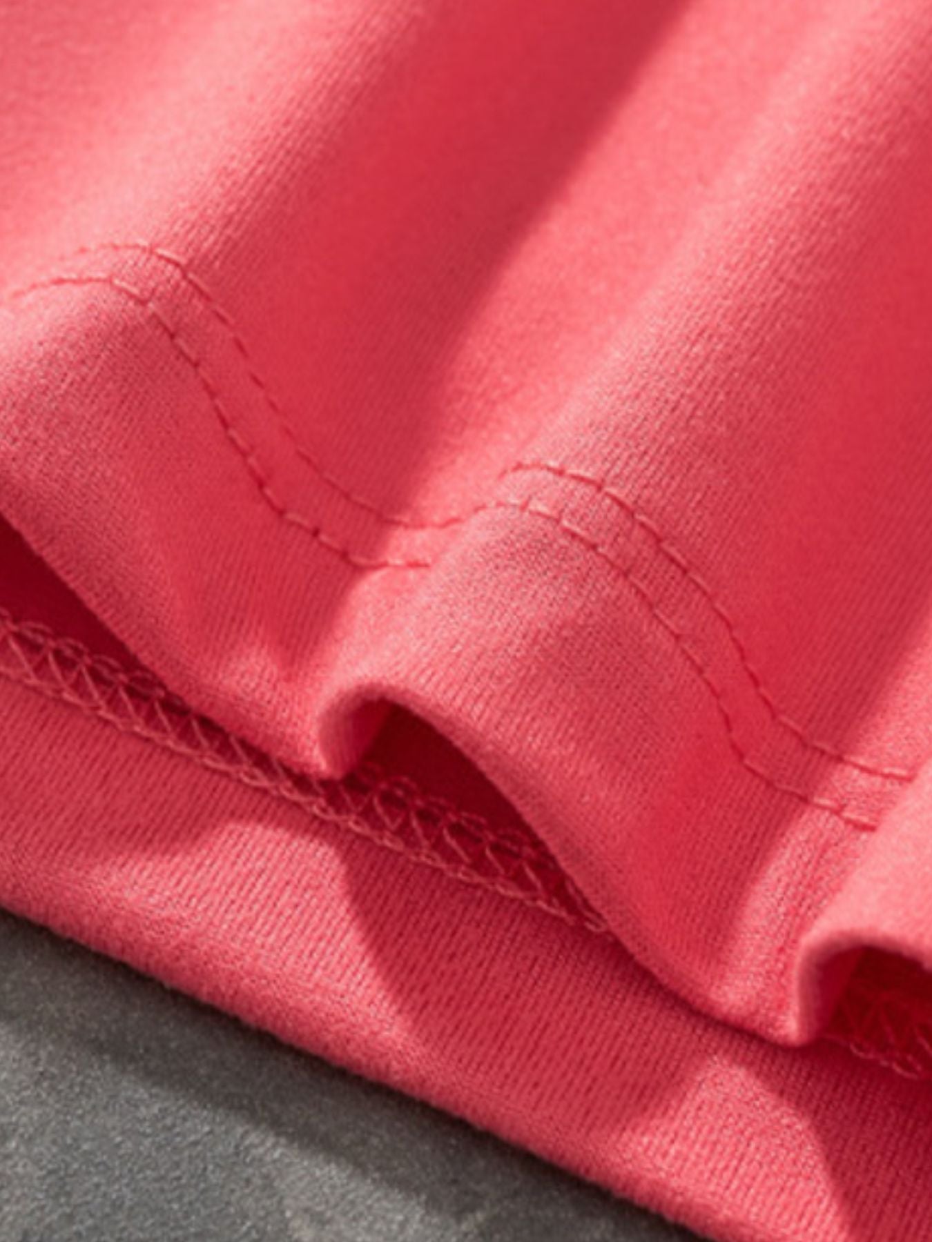 Close-up of coral children's t-shirt hem showing double stitching and soft jersey fabric