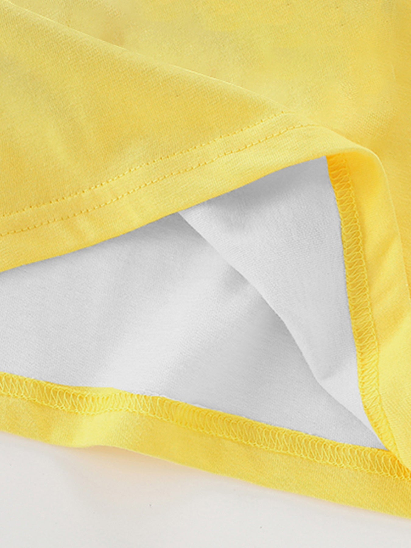 Close-up of the yellow fabric, stitching, and white lining at the hem of the children's t-shirt