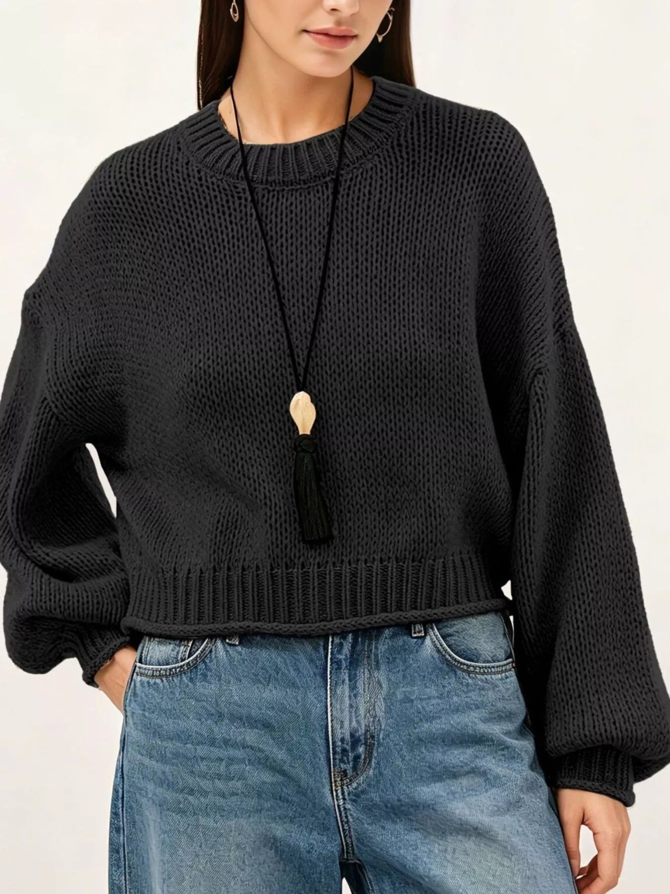 Close on-model front view of a black oversized chunky knit sweater with ribbed hem