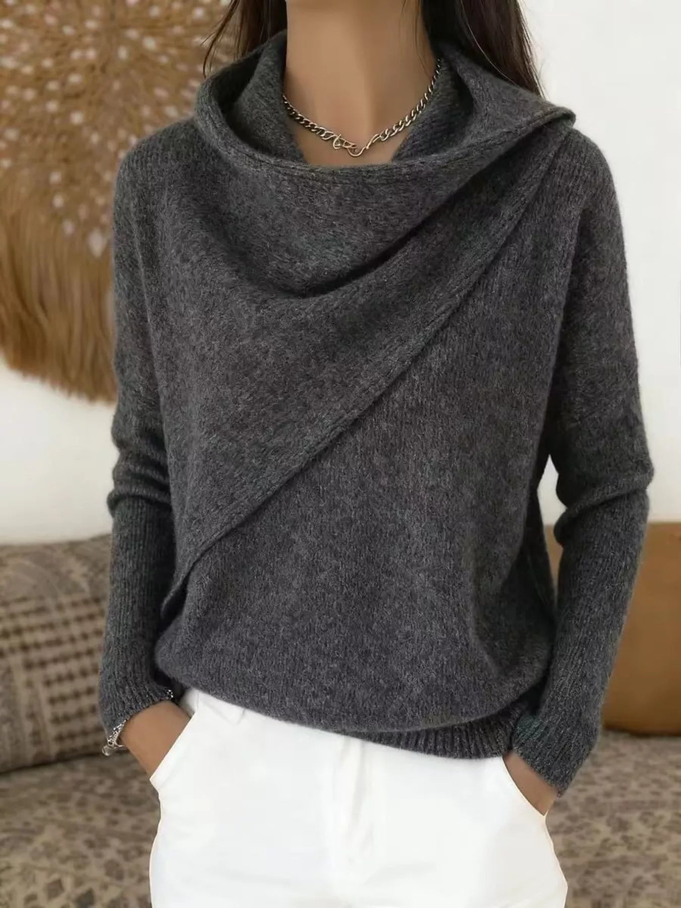 On-model front view of a dark gray cowl neck sweater with a draped asymmetric collar and long sleeves