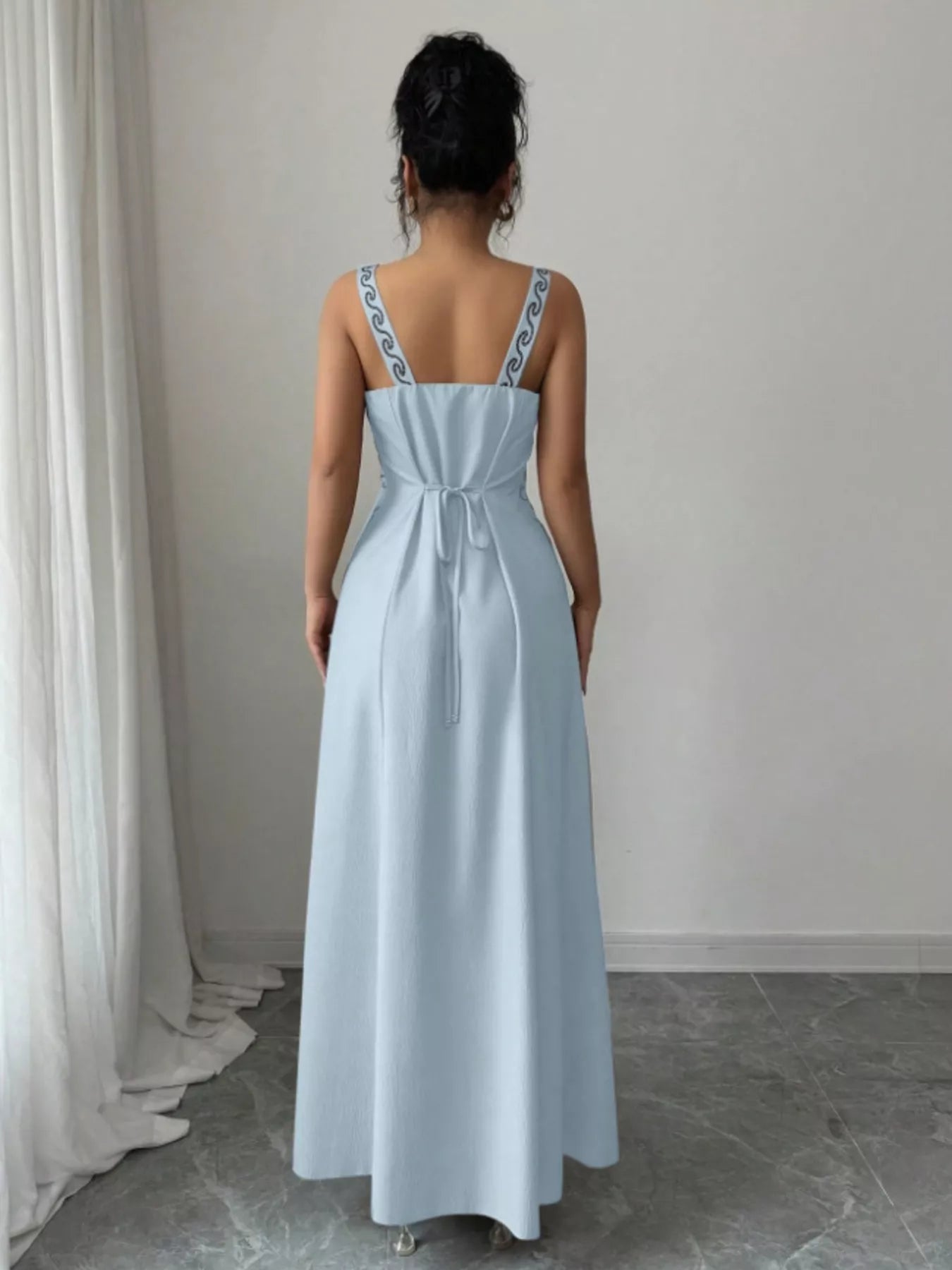 Back view of light blue sleeveless maxi dress with tied waist and patterned straps