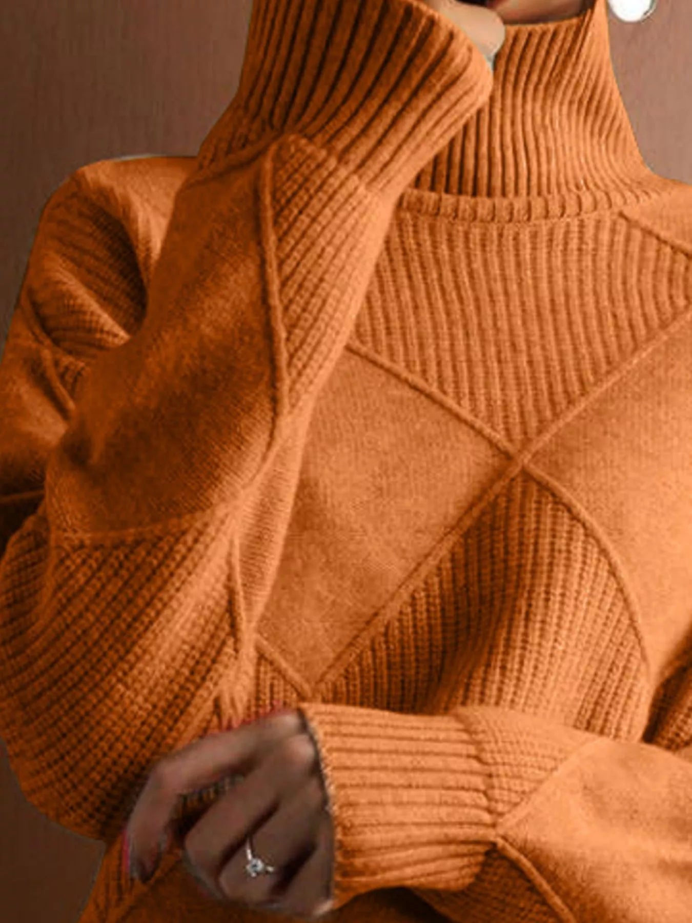 Close up of the tangerine ribbed turtleneck and diamond patterned shoulder