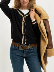 On-model front view of black button down cardigan with cream and brown striped trim layered over white top