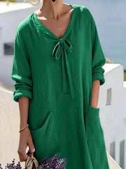 Cropped front view of green long sleeve loose maxi dress, showing tie neck and large pockets