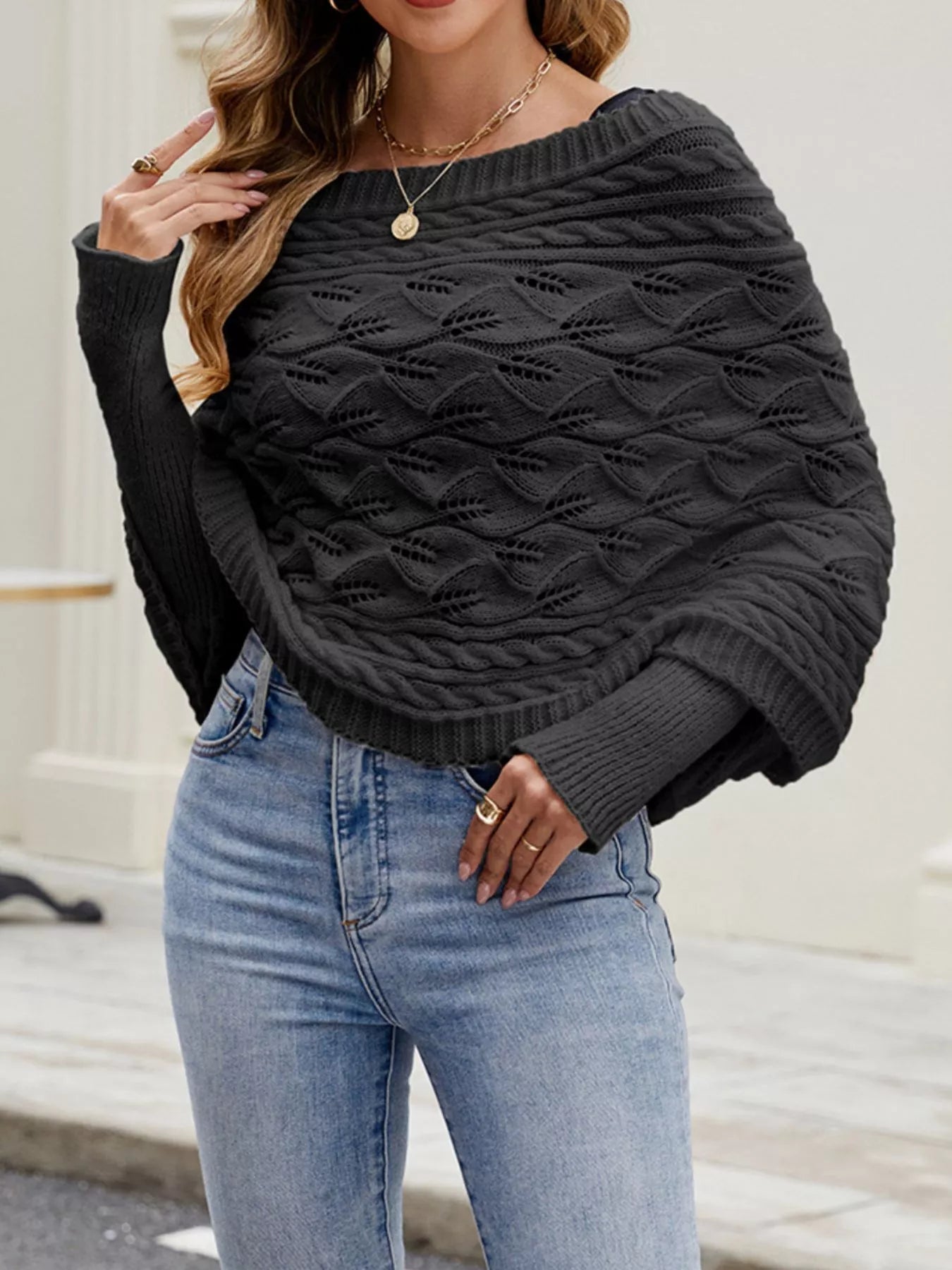 Front view of black batwing sweater with wide neckline and cable knit texture.