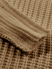 Close view of taupe knit fabric and ribbed cuff of a chunky slouchy sweater.