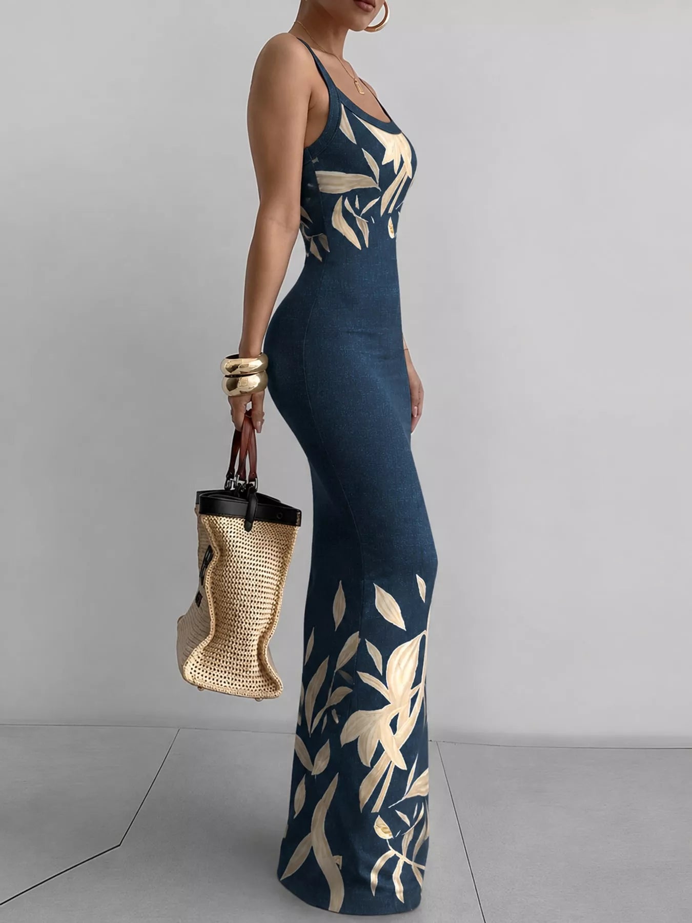 Navy blue sleeveless bodycon maxi dress with cream leaf print shown in side profile