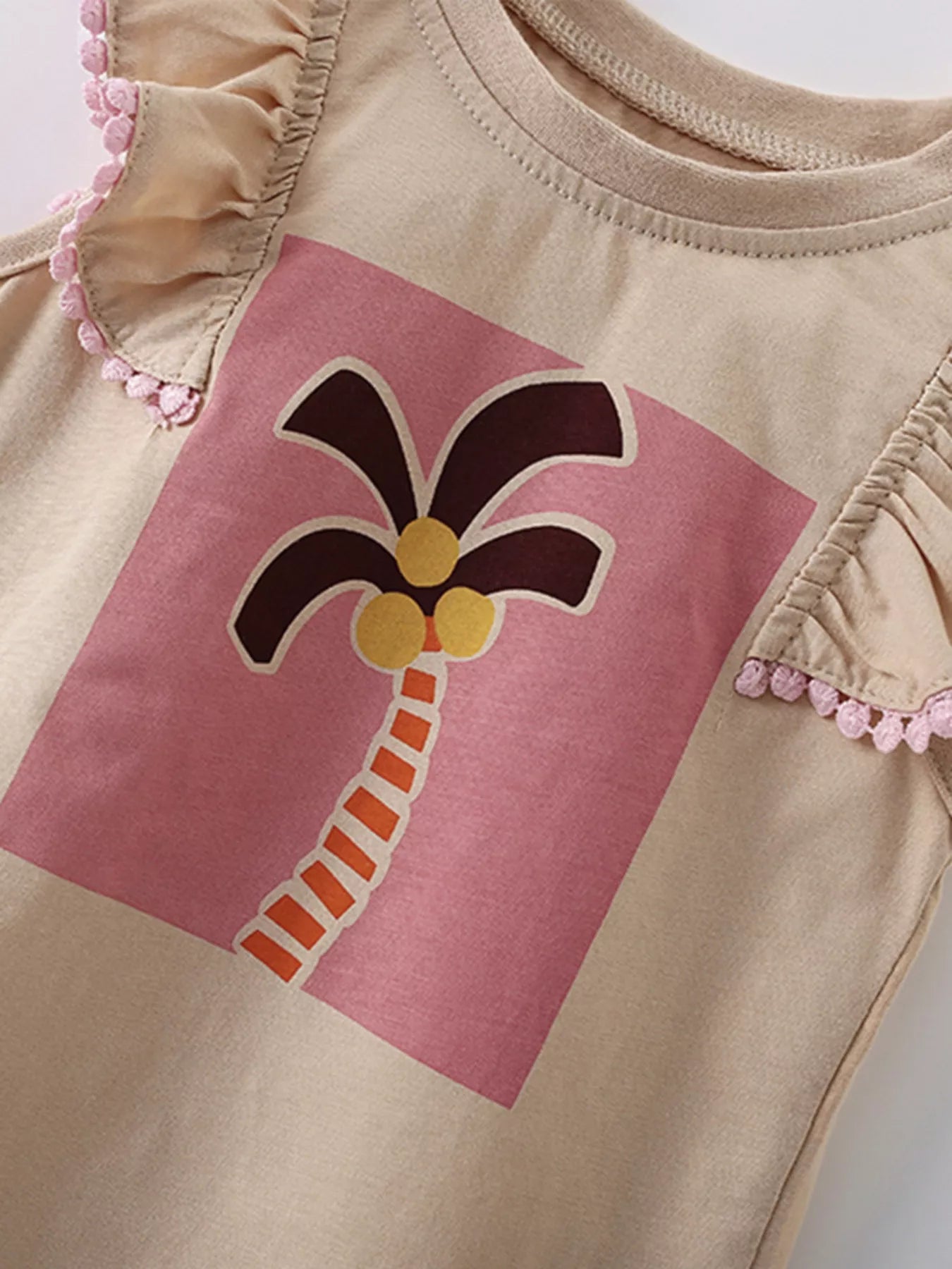 Angled close-up of the palm tree graphic on a pink panel with ruffle trim visible