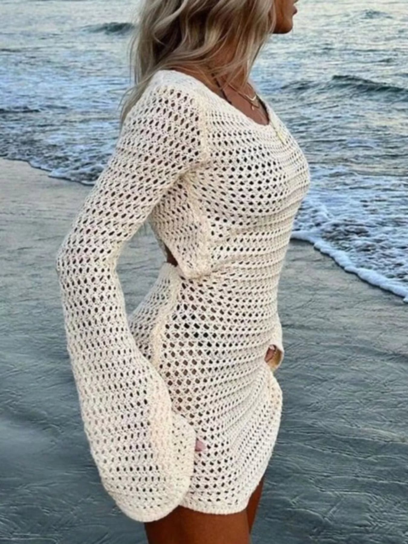 Side view of cream open crochet knit dress with flared sleeves at the beach