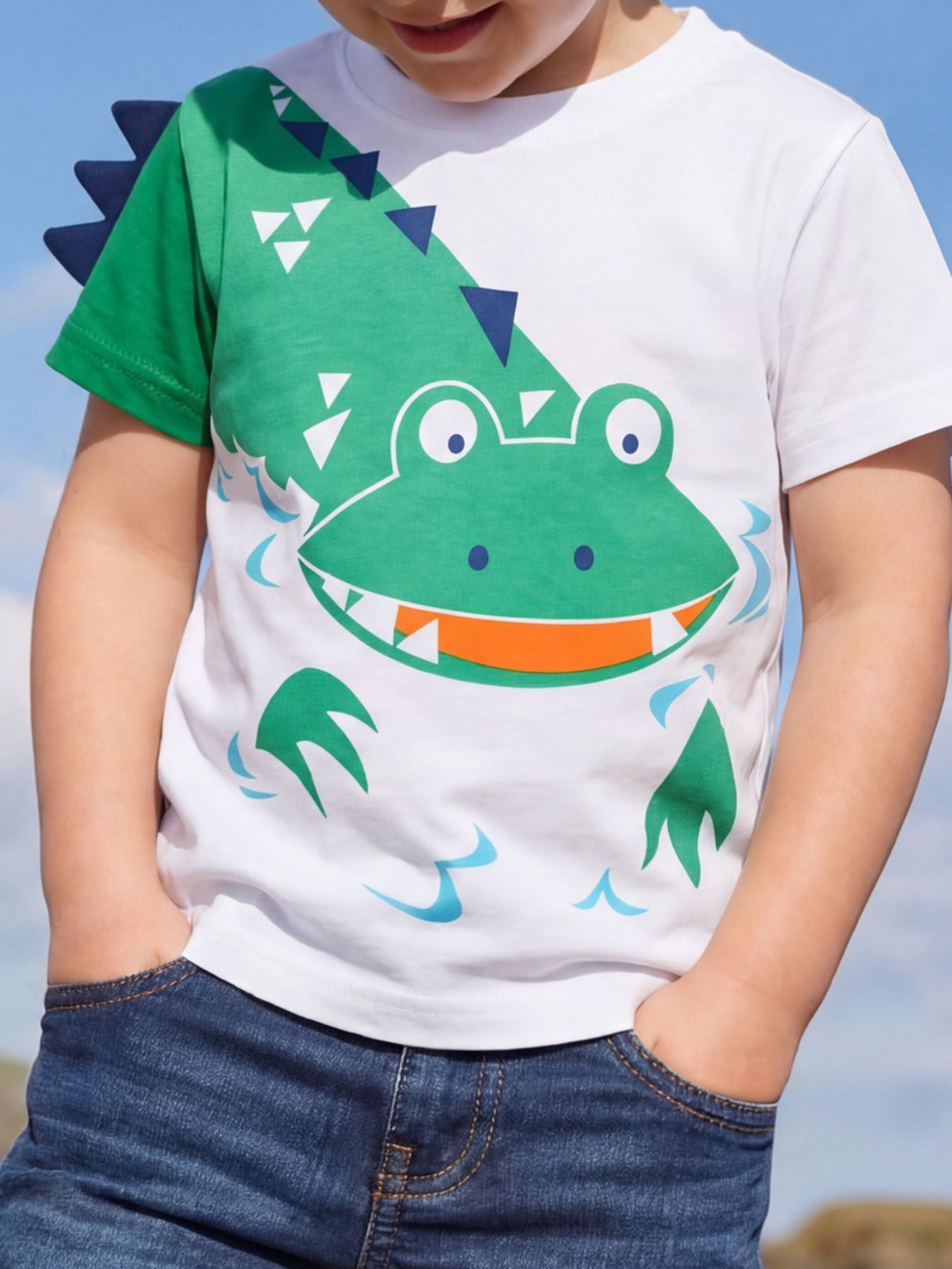 Front view of a white children's t shirt with a large green smiling crocodile graphic