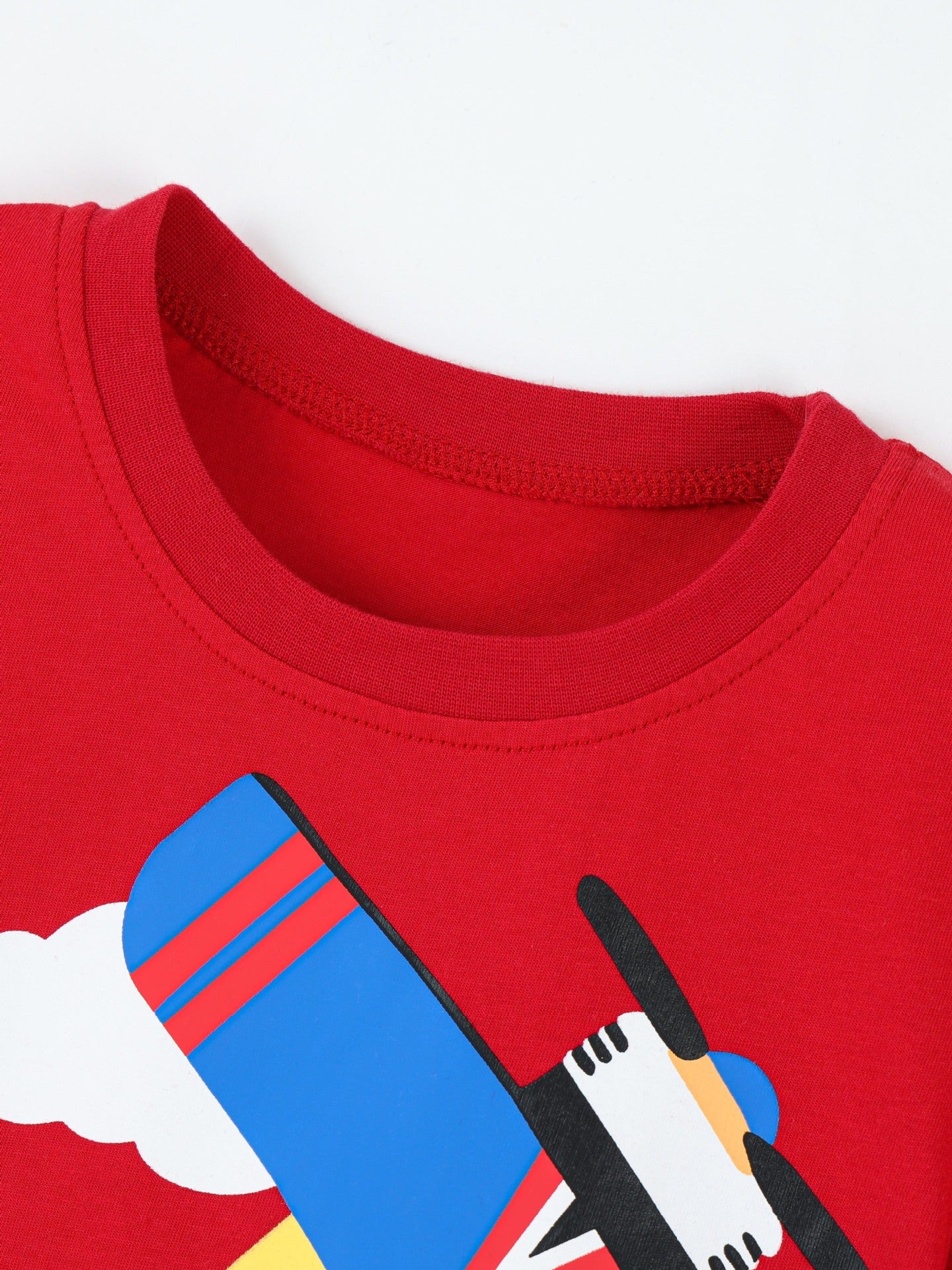 Close-up of red children's t-shirt crew neckline and stitching, with airplane graphic below