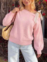 Front view of a pink one-shoulder sweater with a cream bow tie at the shoulder