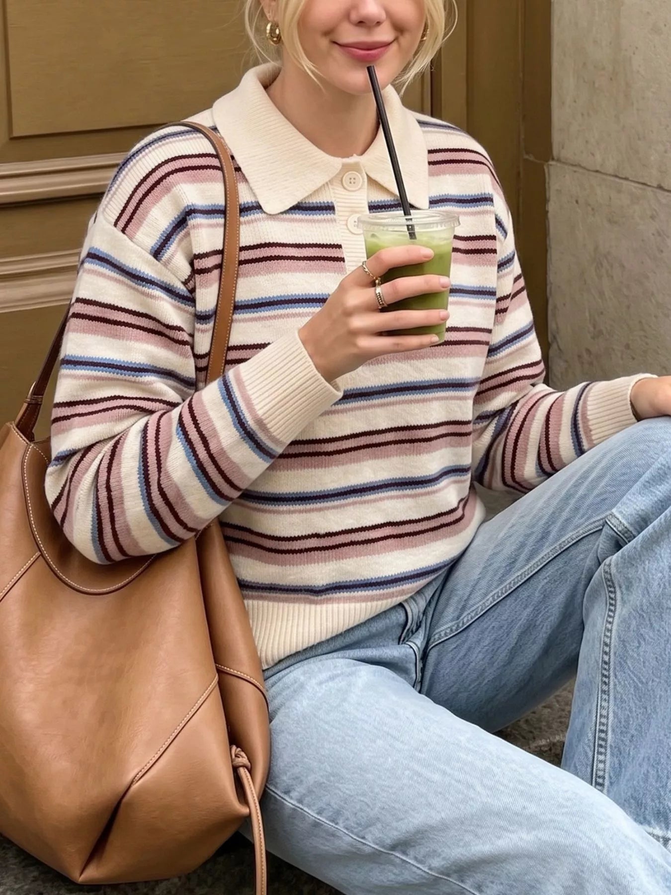 Seated front view of a cream striped polo sweater with pink and blue stripes