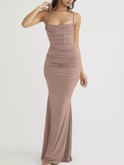 Front view of a dusty pink ruched spaghetti strap bodycon maxi dress with one hand raised
