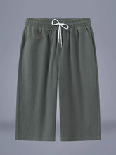 Men's army green cropped casual pants with a drawstring waist and pockets.