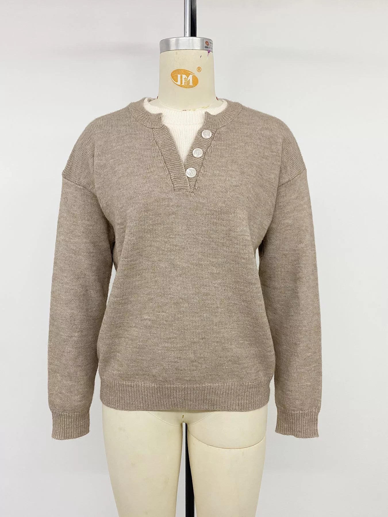 Khaki dropped shoulder sweater with V neck button placket on mannequin, front view