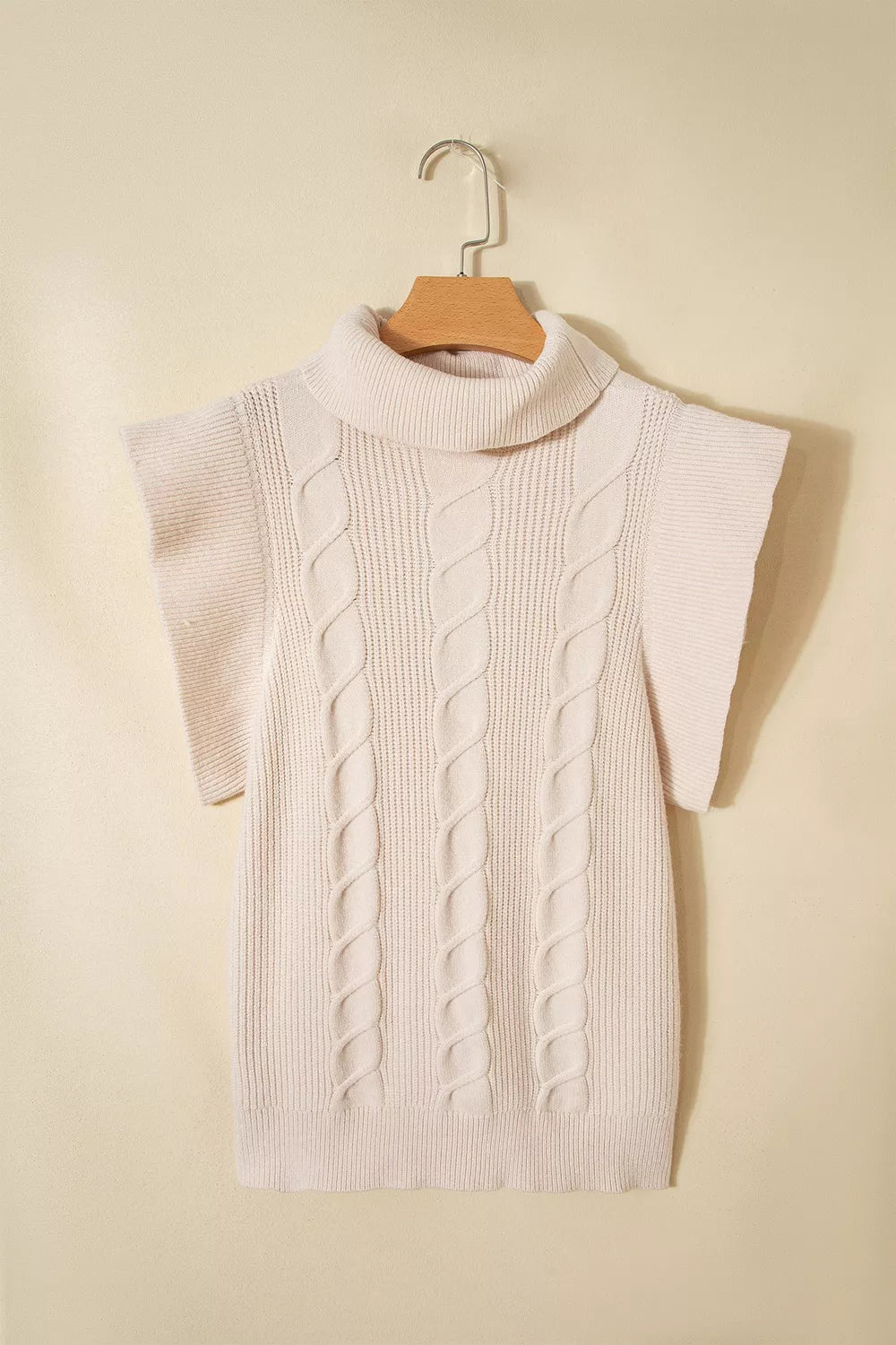 Hanging front view of a cream cable knit turtleneck sweater with ruffled short sleeves