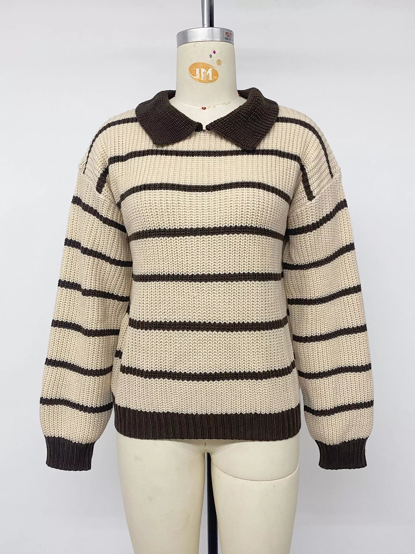 Front view on a mannequin of a cream and brown striped knit polo sweater.
