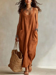 Model wearing brown sleeveless scoop neck maxi dress, full view with large front pockets