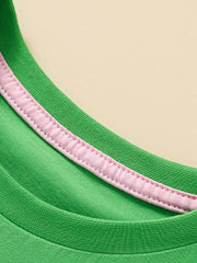 Close view of the green round neckline with pink inner trim and stitching on the children's T-shirt
