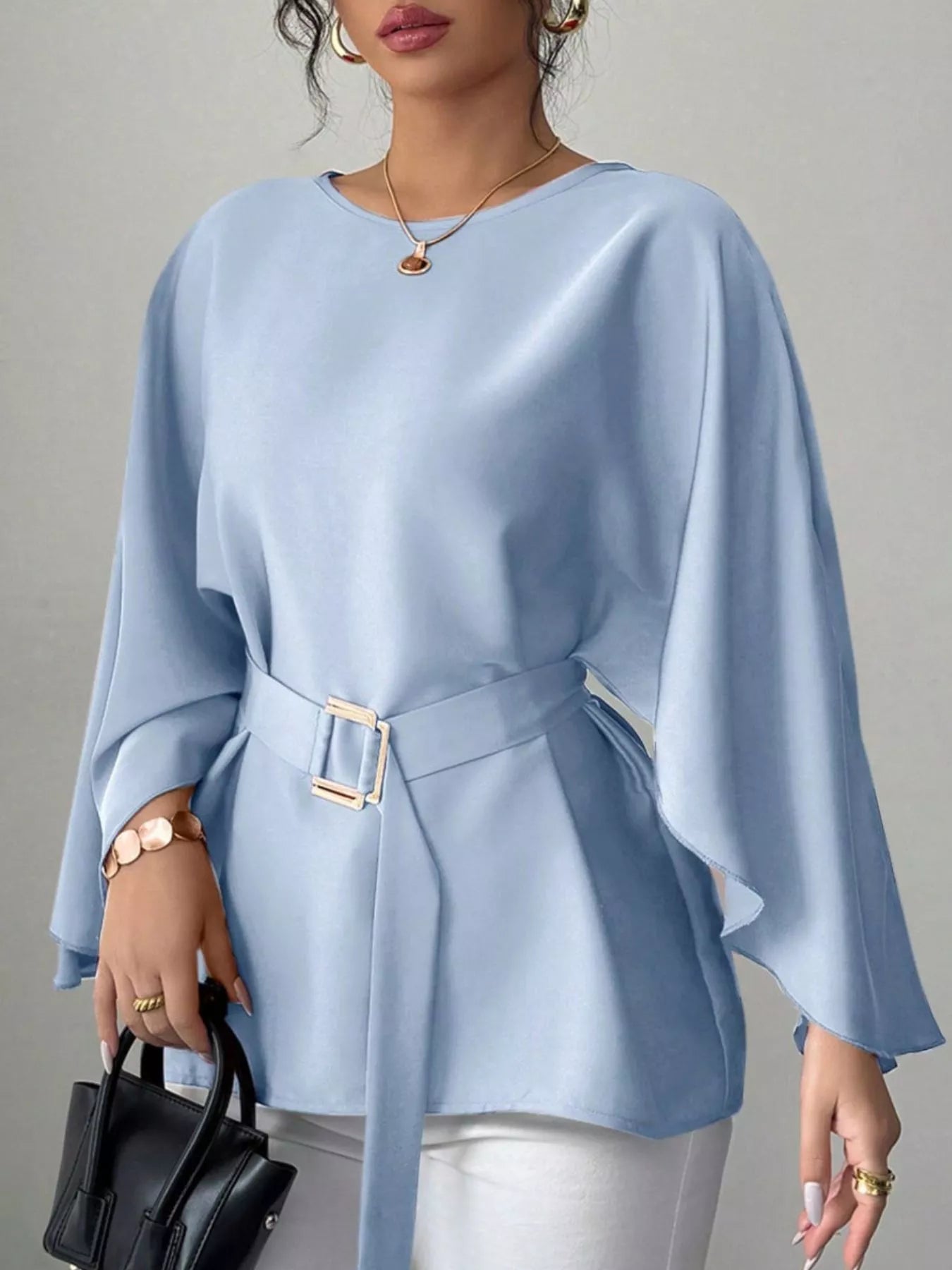 Light blue round neck blouse front view holding black handbag with gold buckle belt