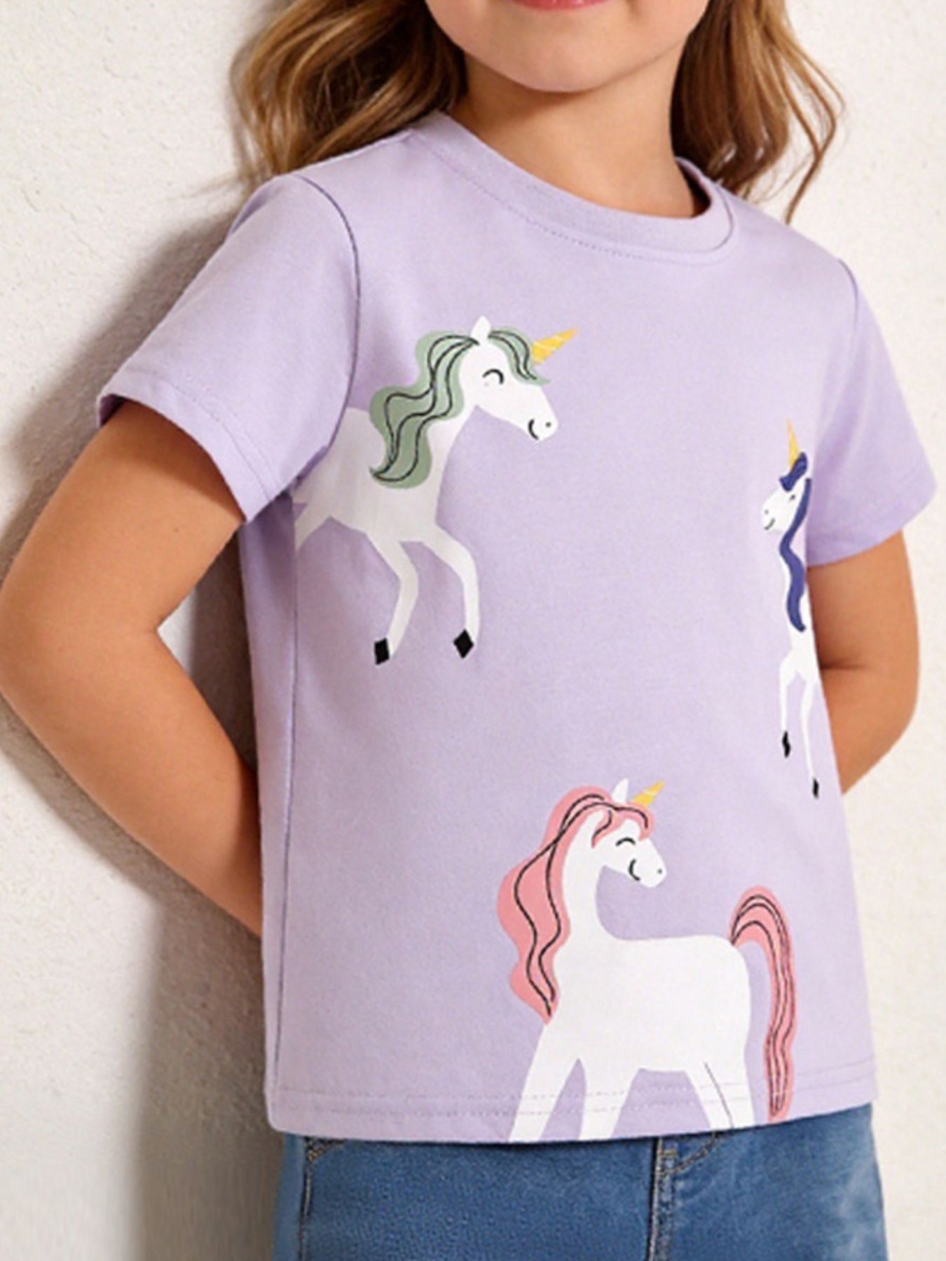 Light purple children's T-shirt with three white unicorns with green, purple and pink manes, front view