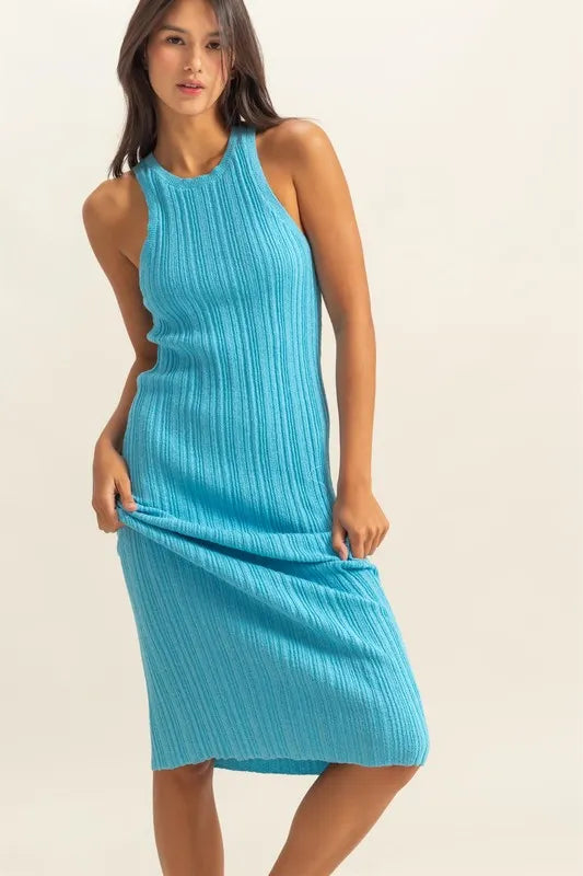 Three quarter front view of bright blue ribbed knit bodycon dress with model holding the skirt