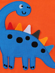 Close view of the blue dinosaur applique with black spots and colourful spikes on orange fabric