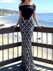 Front view of black off shoulder maxi dress with rhinestone skirt on a beach boardwalk