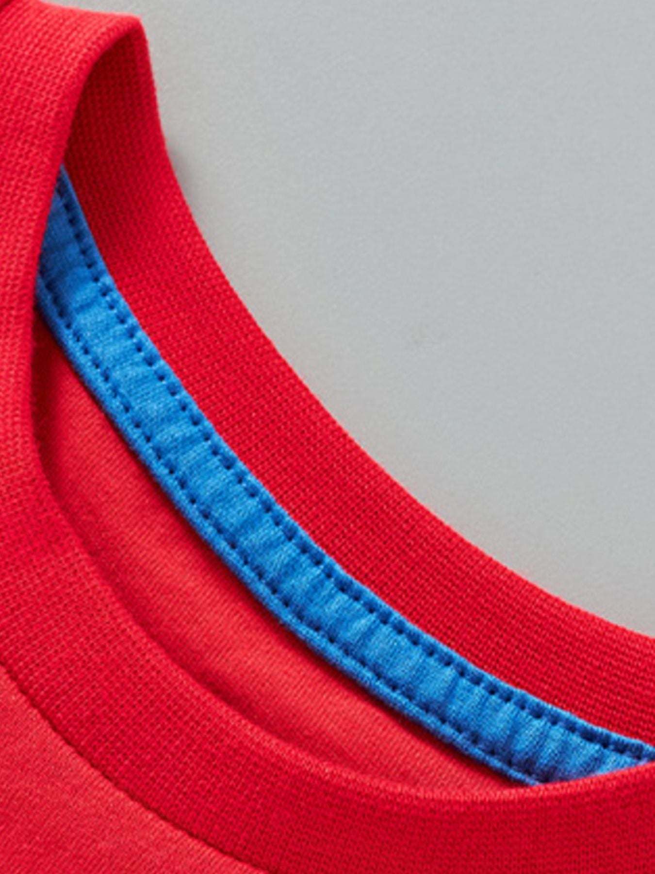 Close-up detail of the red round neckline with blue inner trim on children's rocket T-shirt