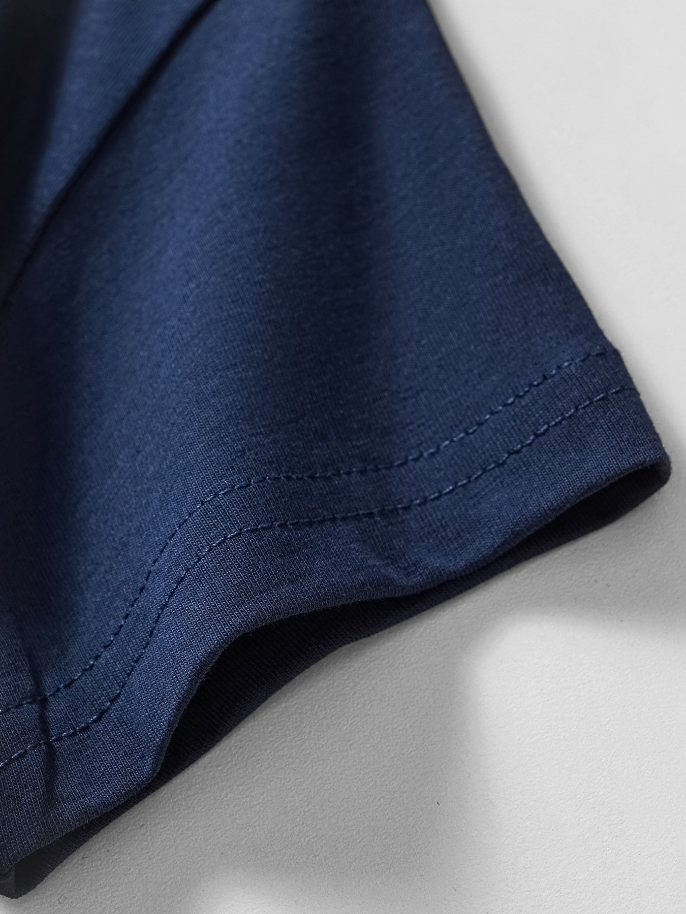 Close view of the stitched short sleeve hem on the dark navy children's t-shirt