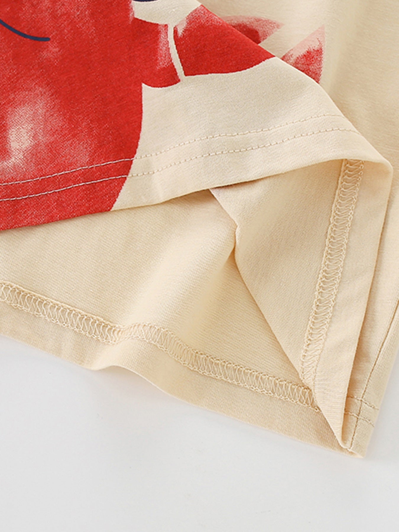 Close-up of the hem stitching and soft cotton fabric on the children's apricot tee