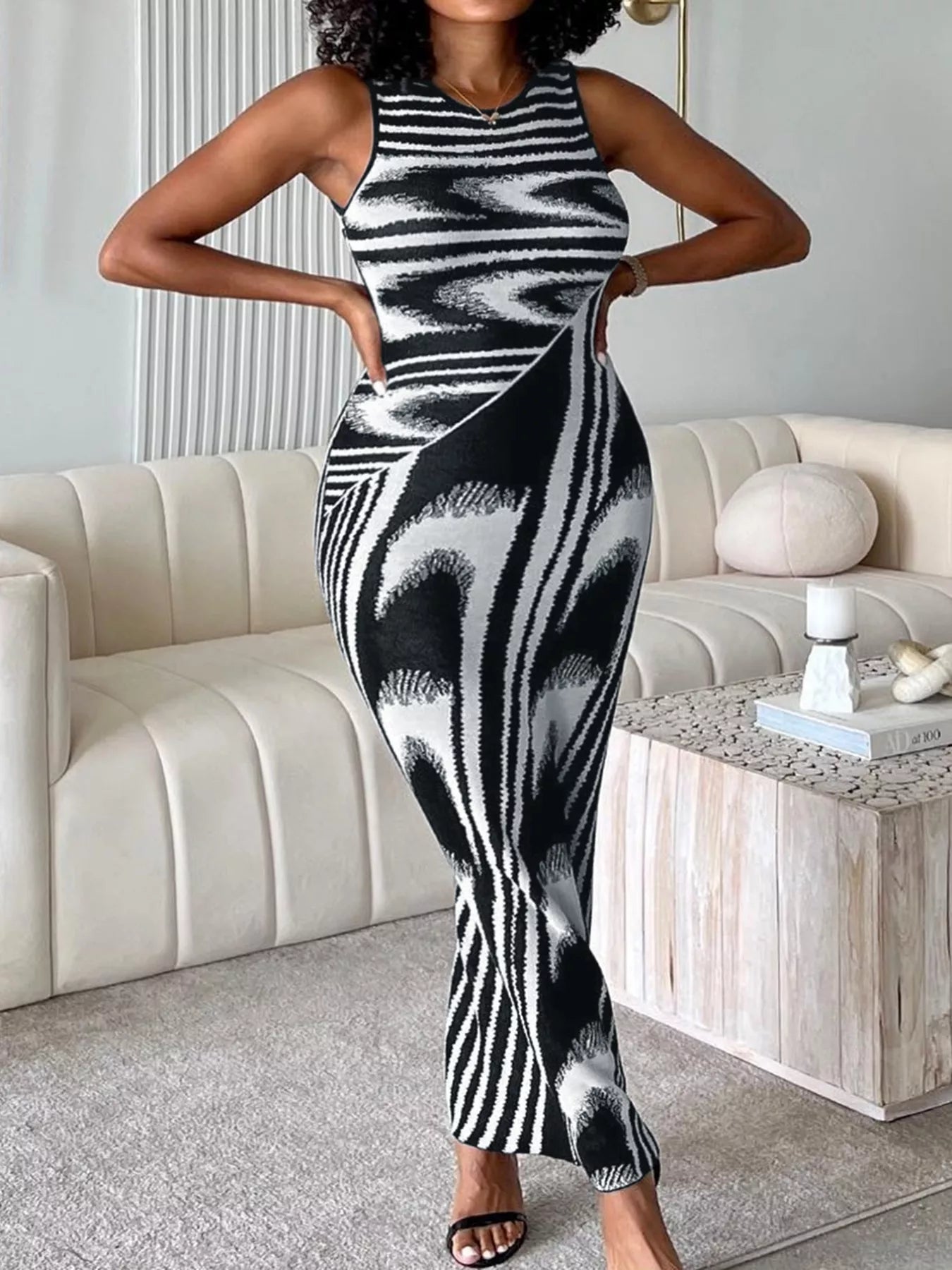 Front view of a plus size black and white sleeveless bodycon maxi dress in a living room