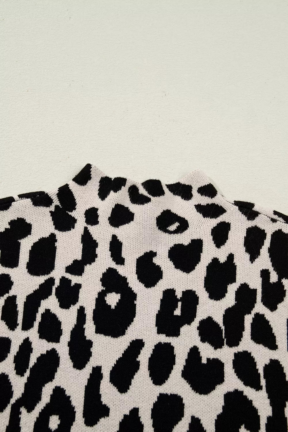 Close up detail of the high neckline and leopard print knit on the cream and black sweater.
