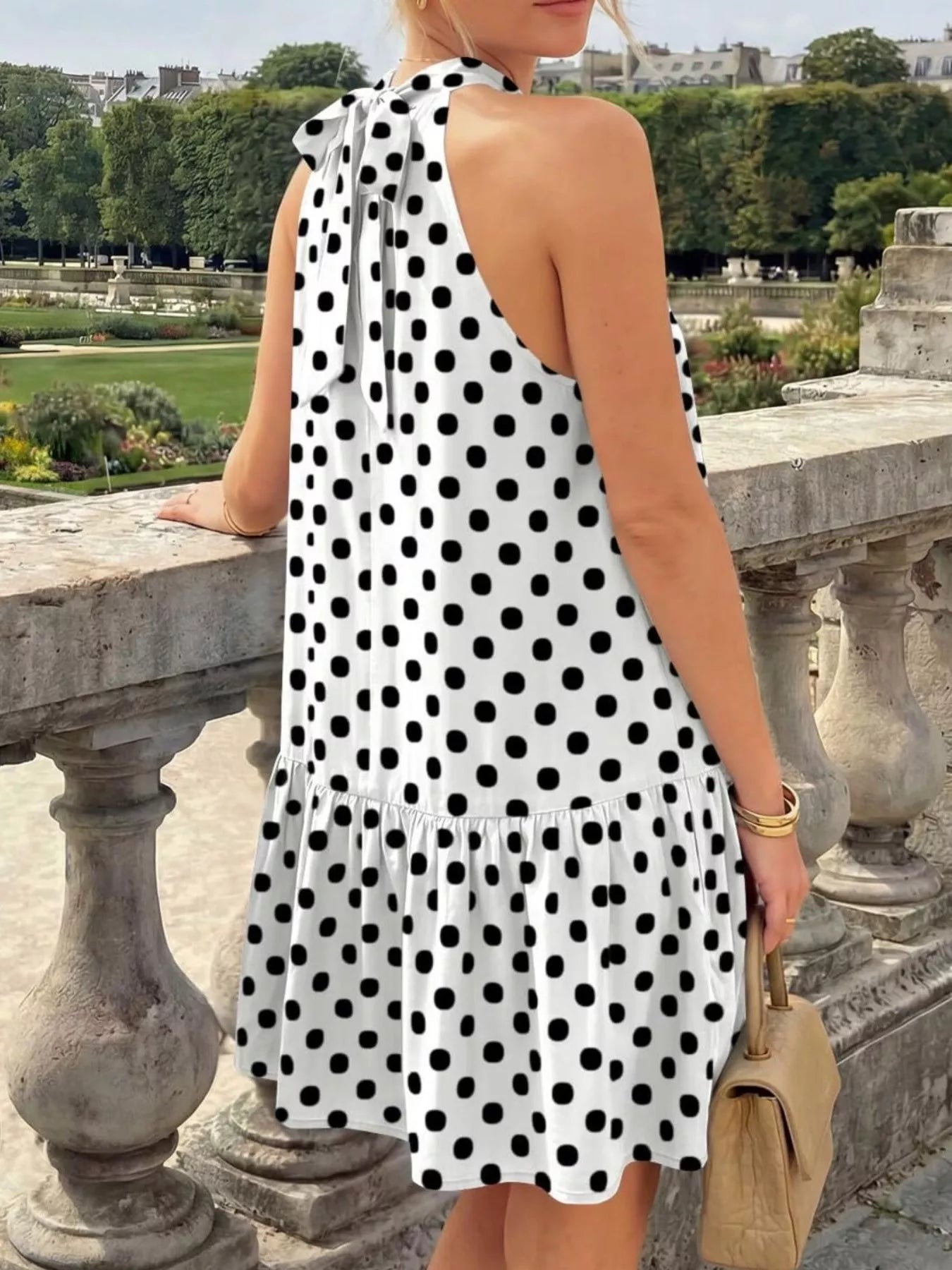 Back view of the white polka dot halter neck mini dress with a neck tie
