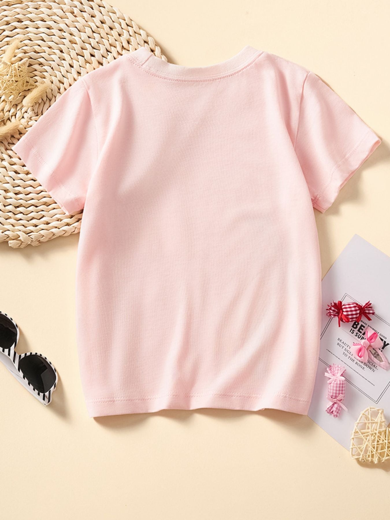 Back view of the plain blush pink children's short sleeve tee laid flat