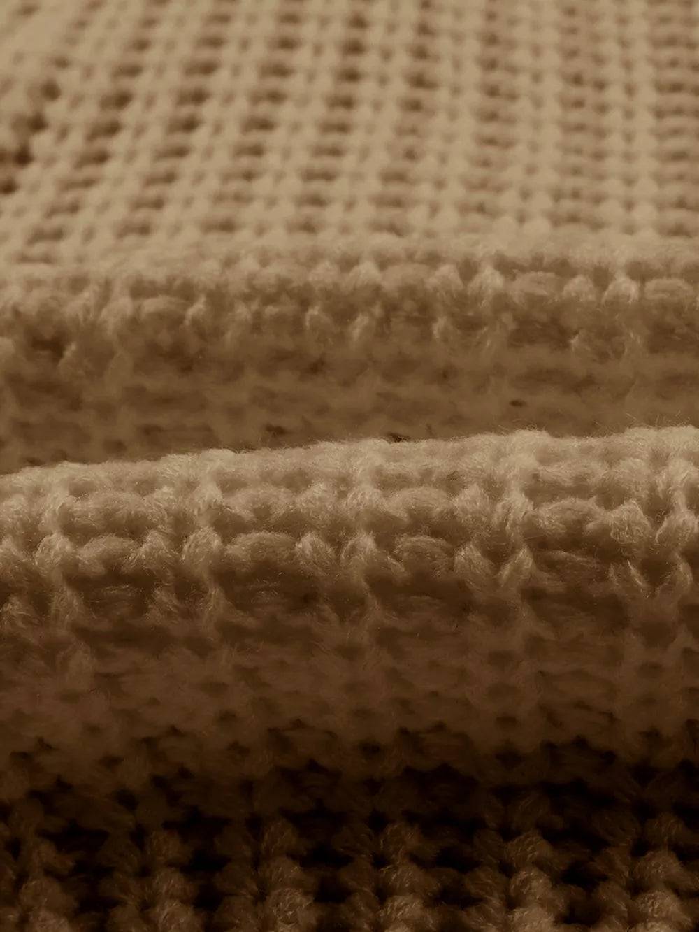 Close view of taupe chunky ribbed knit texture showing thick soft yarn detail.