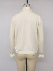 Back view of cream V neck knit top with ruffle cuffs displayed on mannequin
