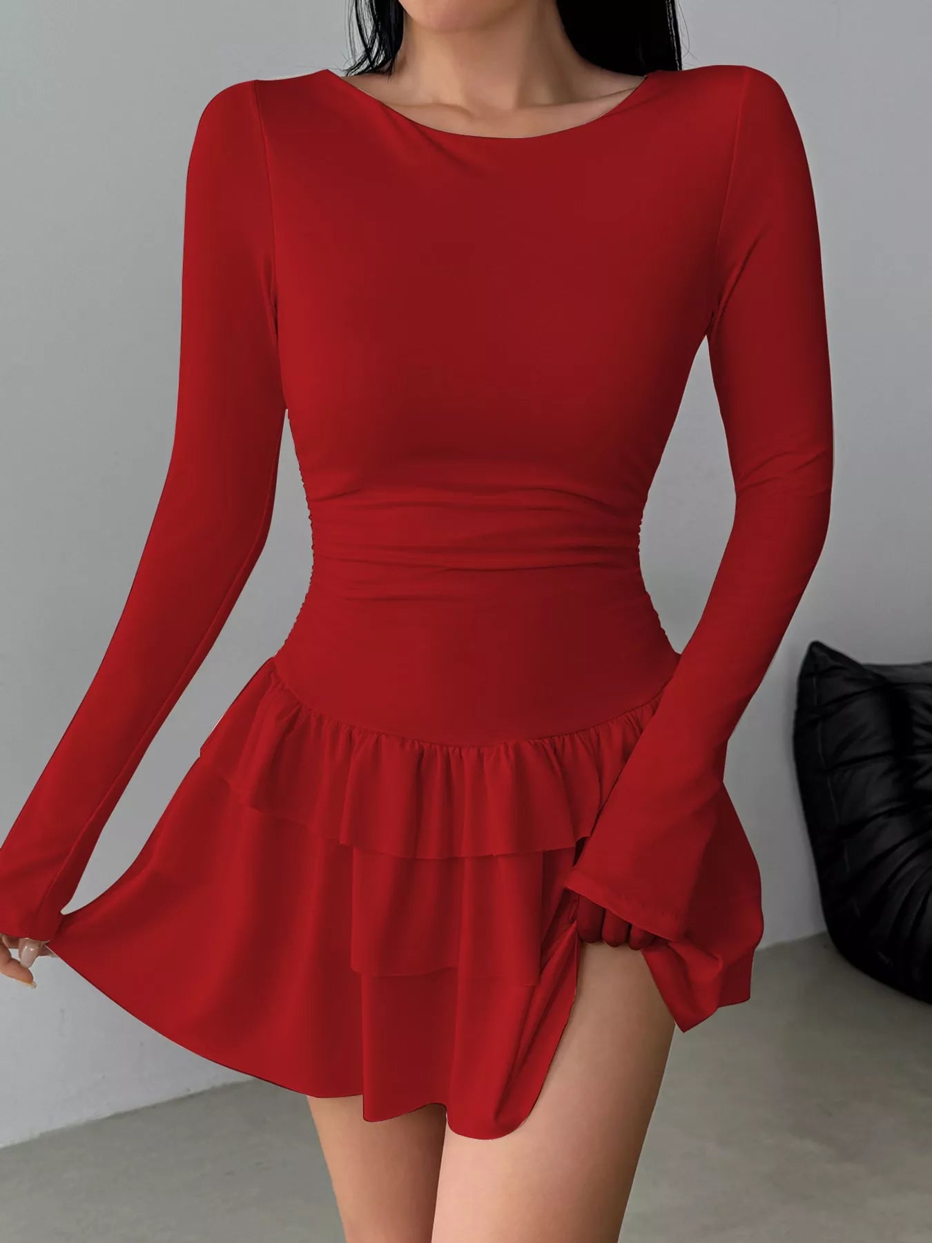 Red long sleeve mini dress worn front facing while holding out the tiered ruffle skirt