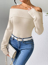 Front view of a beige off shoulder ribbed knit sweater with long sleeves and jeans