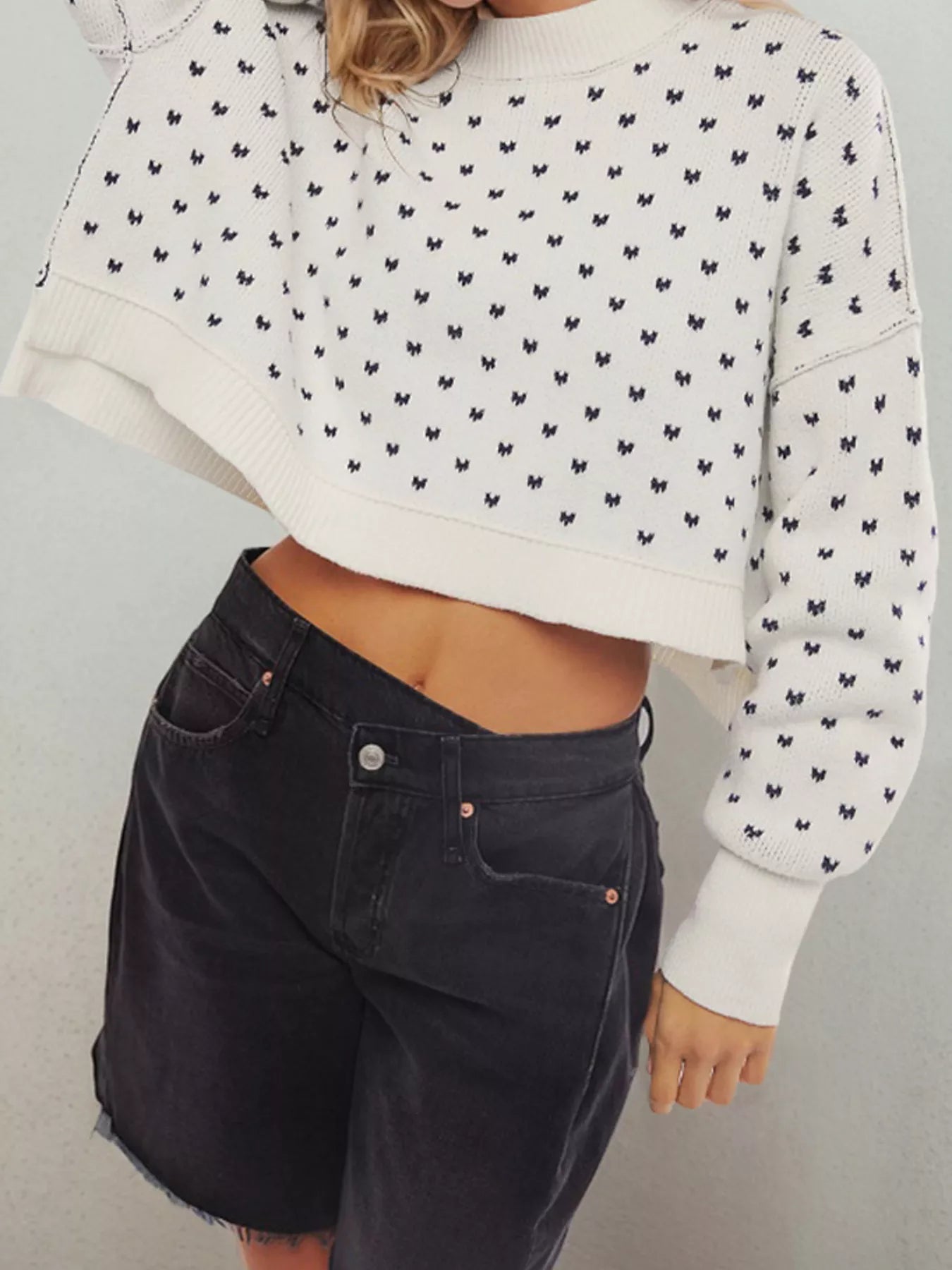 White sweater with small navy bow print, ribbed cuffs and hem, shown from the front