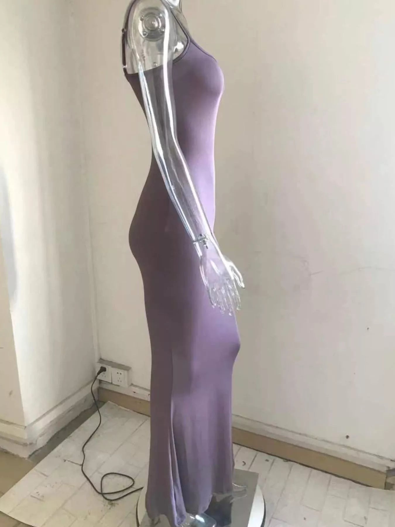 Side profile of a mauve spaghetti strap bodycon maxi dress on a clear mannequin with a flared hem