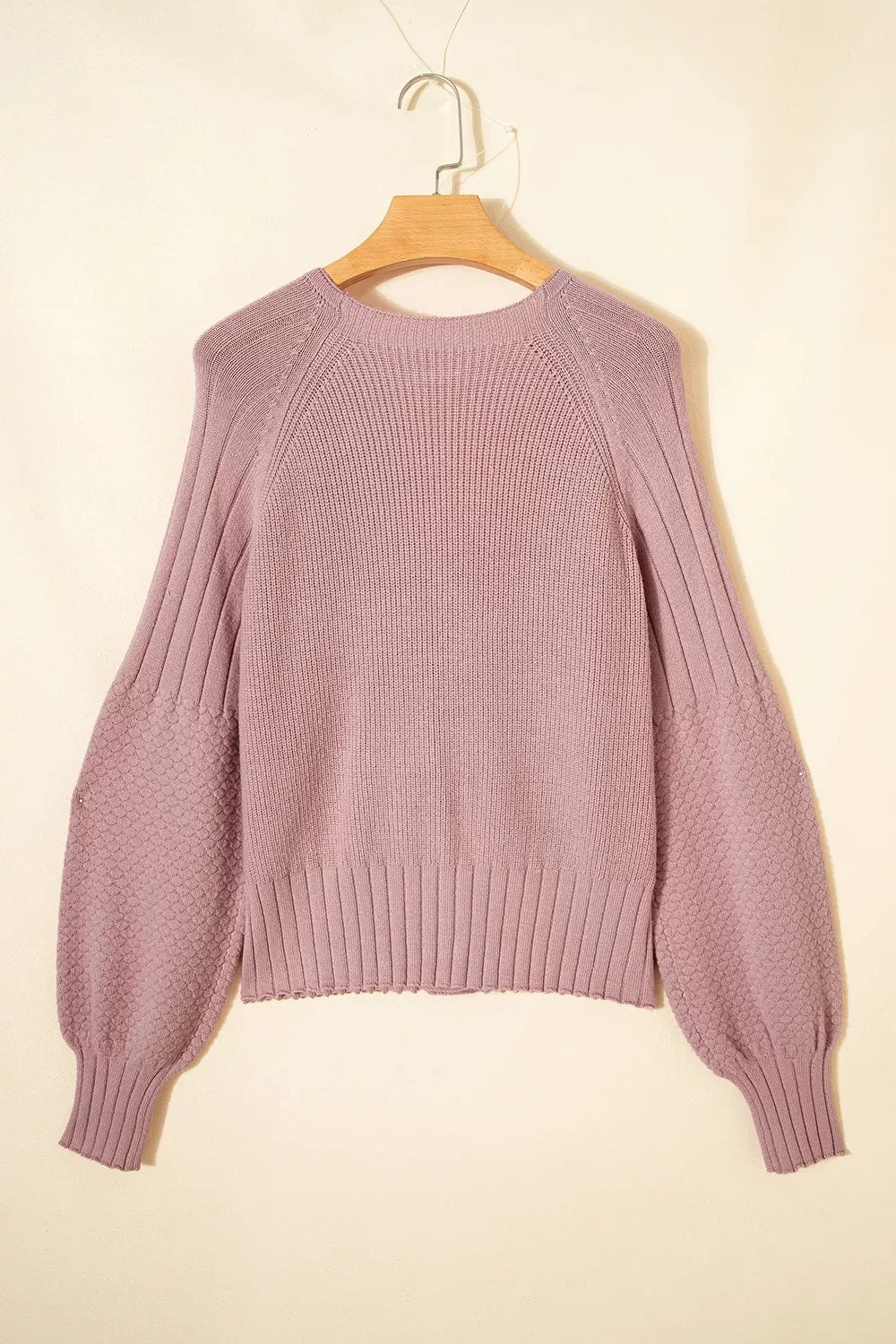Flat lay back view of a dusty pink V-neck cardigan on a hanger with textured sleeves