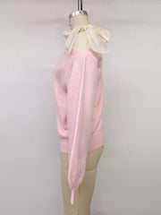 Side view of a pink one-shoulder sweater with a cream bow on a mannequin