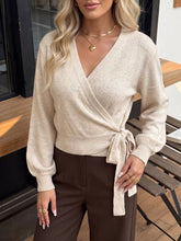 Front view of a pale beige wrap sweater with a side tie and balloon long sleeves